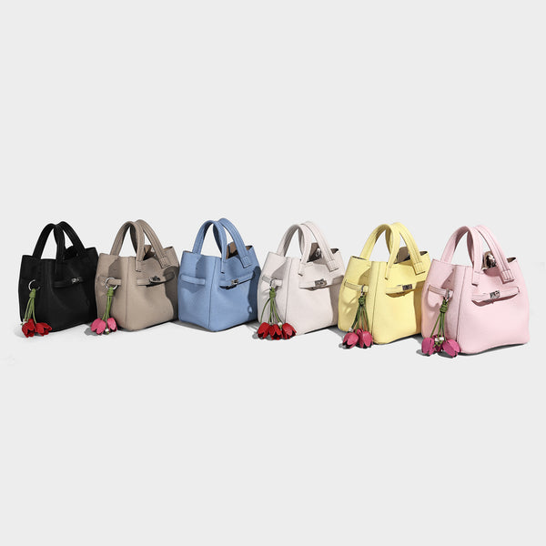 Small structured pebbled bucket tote bag with dual top handles, silver turn-lock front pocket, and detachable shoulder strap