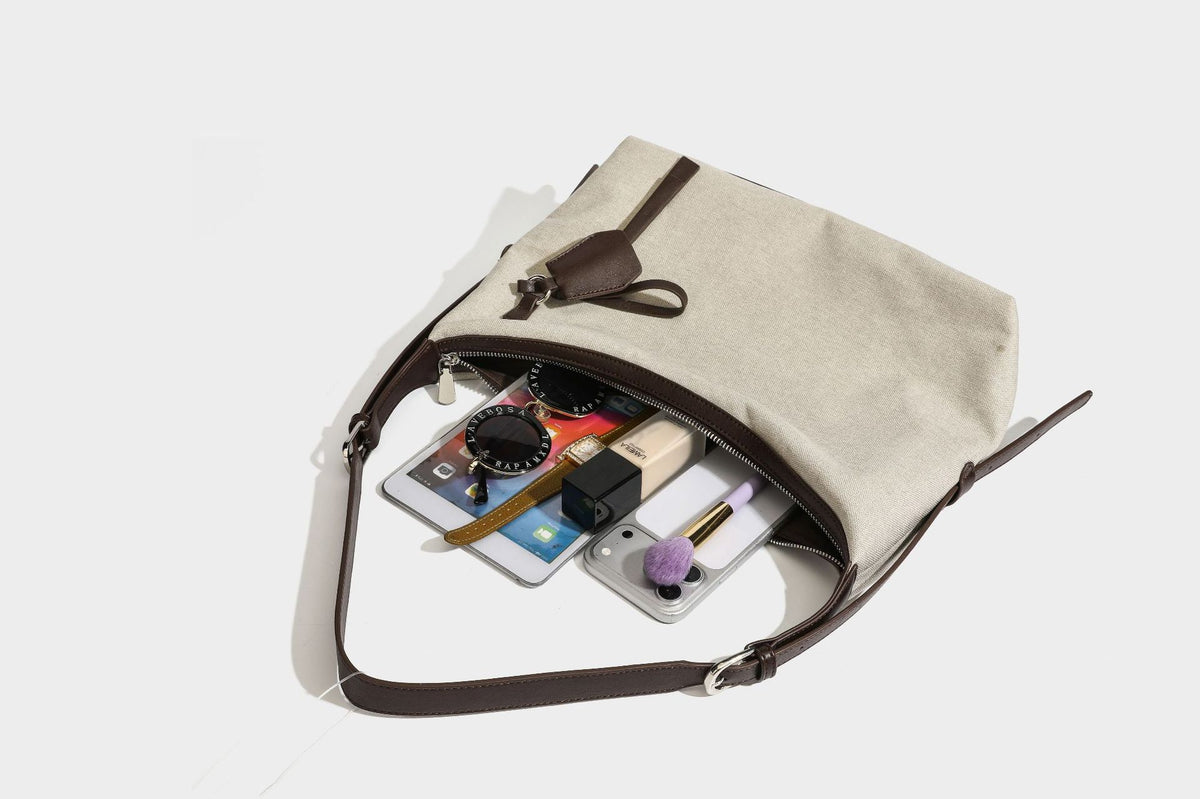 Lässige Hobo-Schultertasche aus haferfarbenem Canvas mit dunkelbraunen Besätzen in Lederoptik, silberfarbenem Reißverschluss und langem, verstellbarem