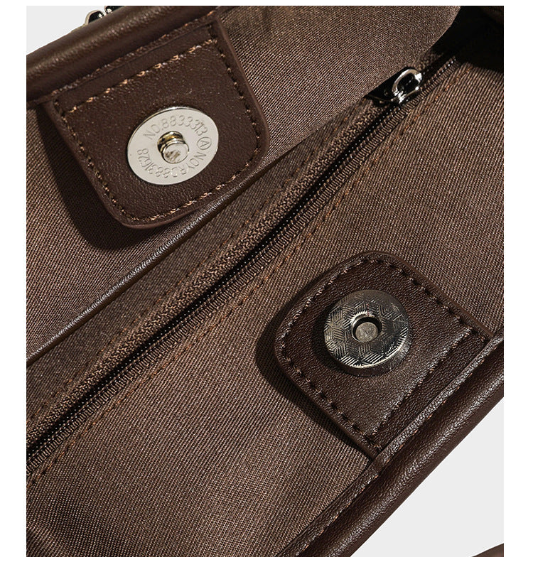 Small structured beige canvas top-handle bag with dark brown leather-look trim, silver turn-lock hardware, and detachable