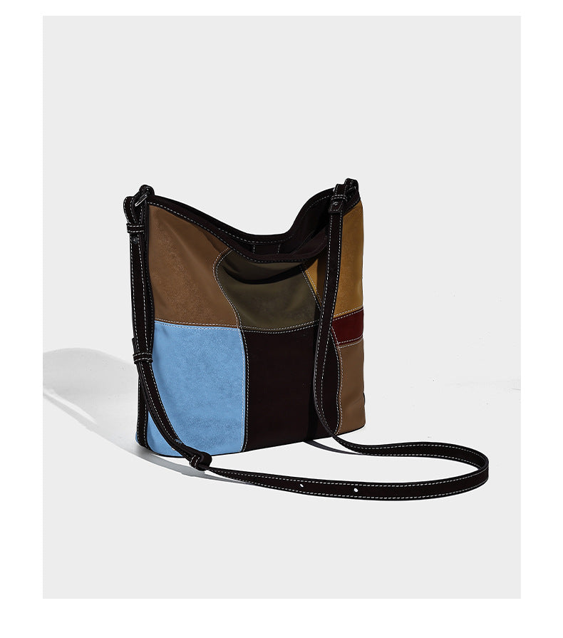 Lässig geschnittene Patchwork-Bucket-Bag mit dunkelbraunen, beigefarbenen, senfgelben, olivgrünen, roten und hellblauen Partien sowie kontrastfarbenen Nähten