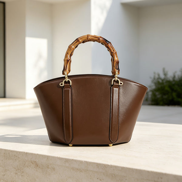 Structured trapezoid handbag with segmented bamboo top handle, smooth leather-look finish, gold-tone hardware, and vertical
