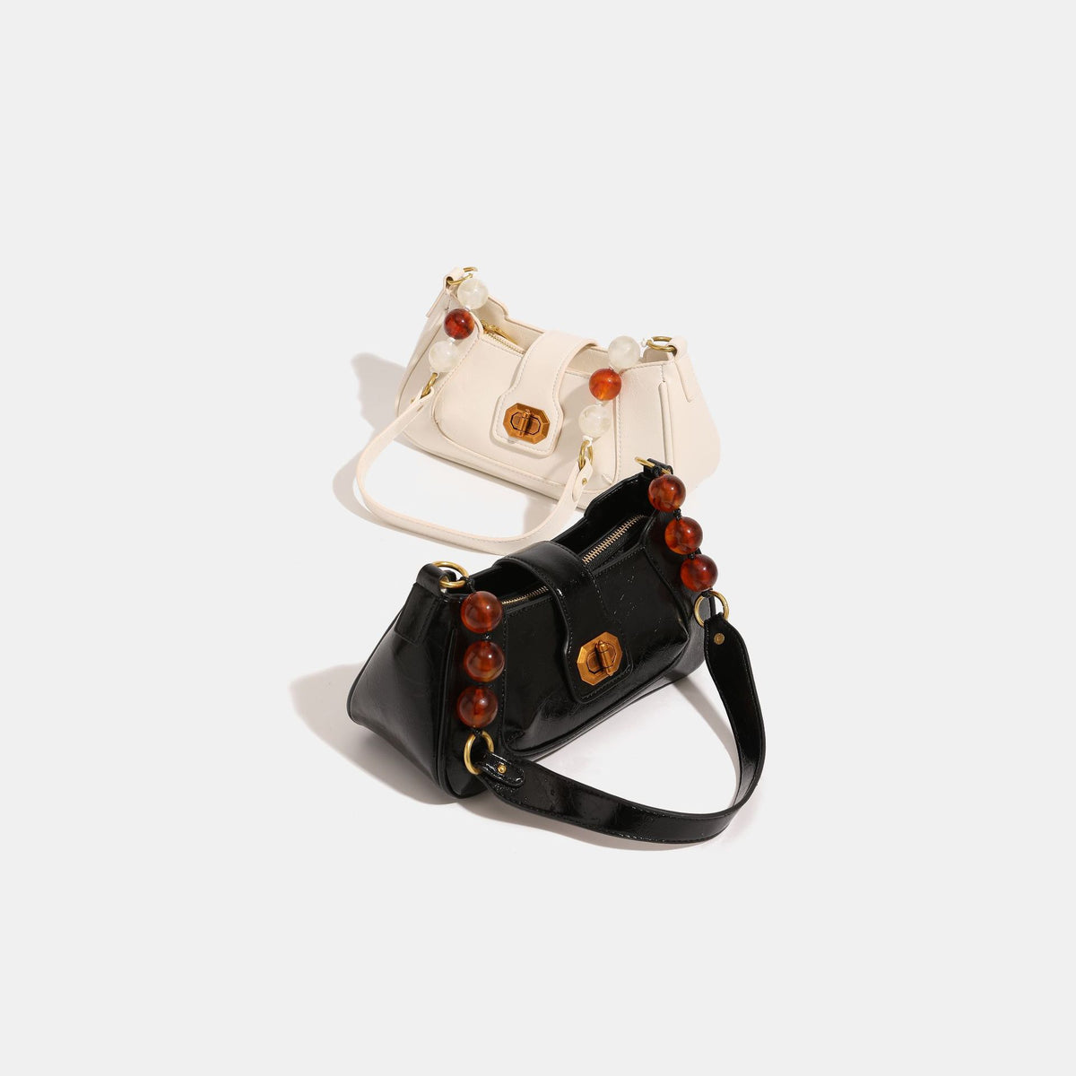 Compact glossy crinkled baguette shoulder bag with amber resin bead strap accent and gold-tone turn-lock closure, detail view