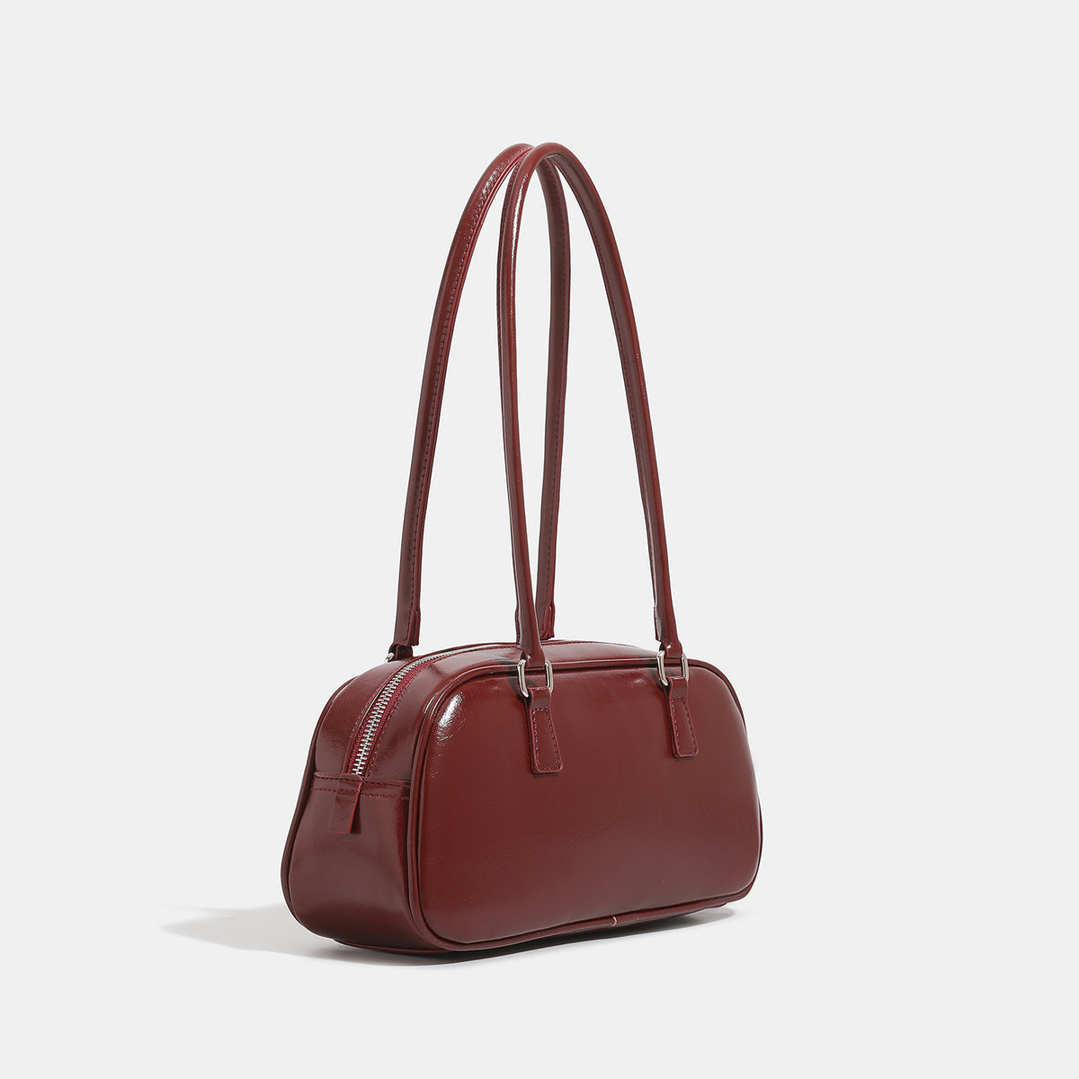 Rounded baguette shoulder bag with glossy leather-look finish, double-pull zip top, dual top handles, and silver-tone, detail