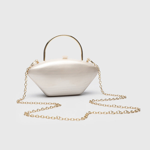 Shell-shaped pearlescent top-handle clutch bag with arched gold-tone metal handle and gold chain strap, detail view 2