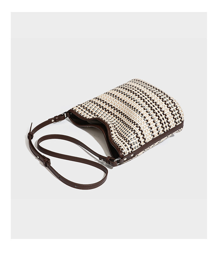 Woven stripe bucket shoulder bag in cream and dark brown with leather-look trim, knotted adjustable strap, and small shield