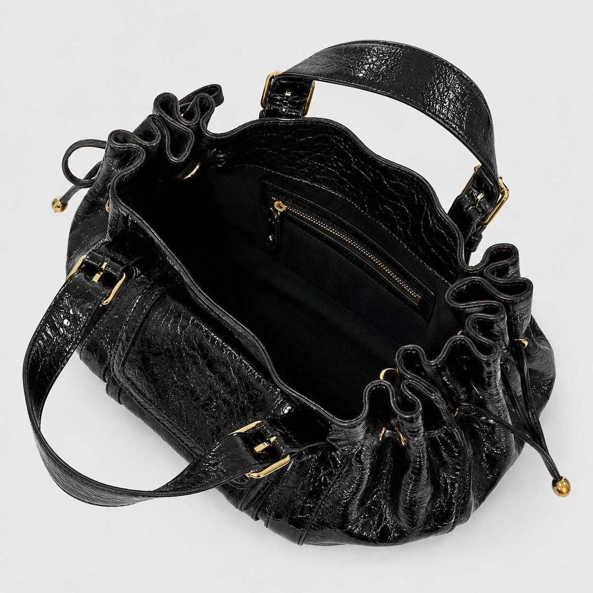 Schwarze Henkeltasche in geknitterter Glanzlederoptik mit seitlichen Kordelzügen, Vordertasche mit Schnalle, zwei Tragegriffen und goldfarbenem