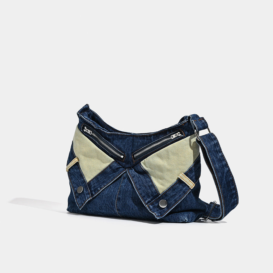 Indigo denim shoulder bag with pale contrast panels, exposed silver-tone zipper, snap-button accents, and long adjustable