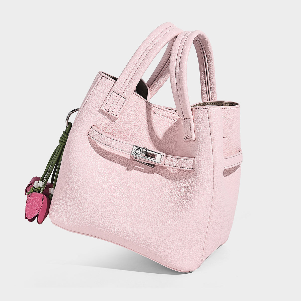Small structured pebbled bucket tote bag with dual top handles, silver turn-lock front pocket, and detachable shoulder strap
