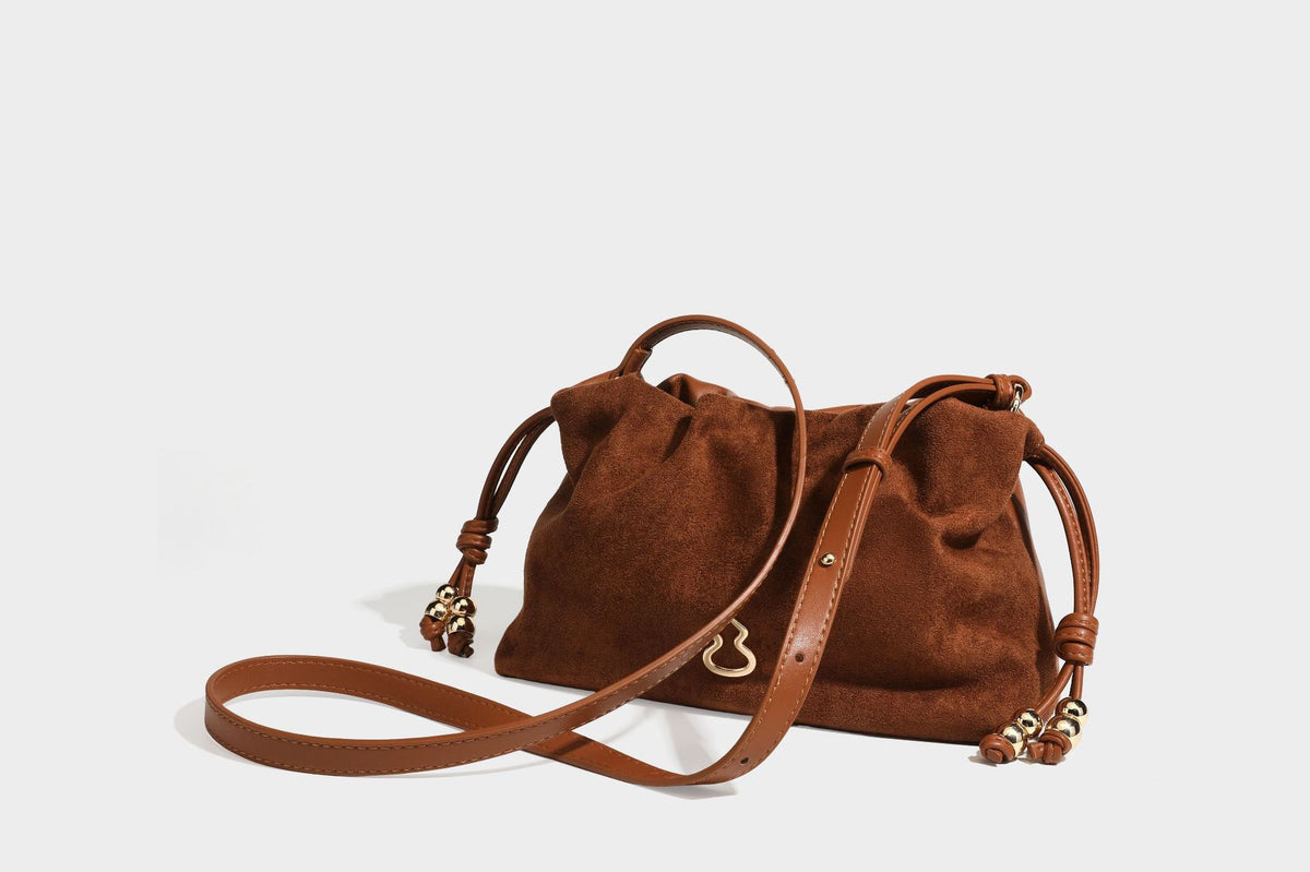 Suede-look drawstring shoulder bag in brown with smooth trim, knotted bead drawstring closure, slim adjustable strap, and