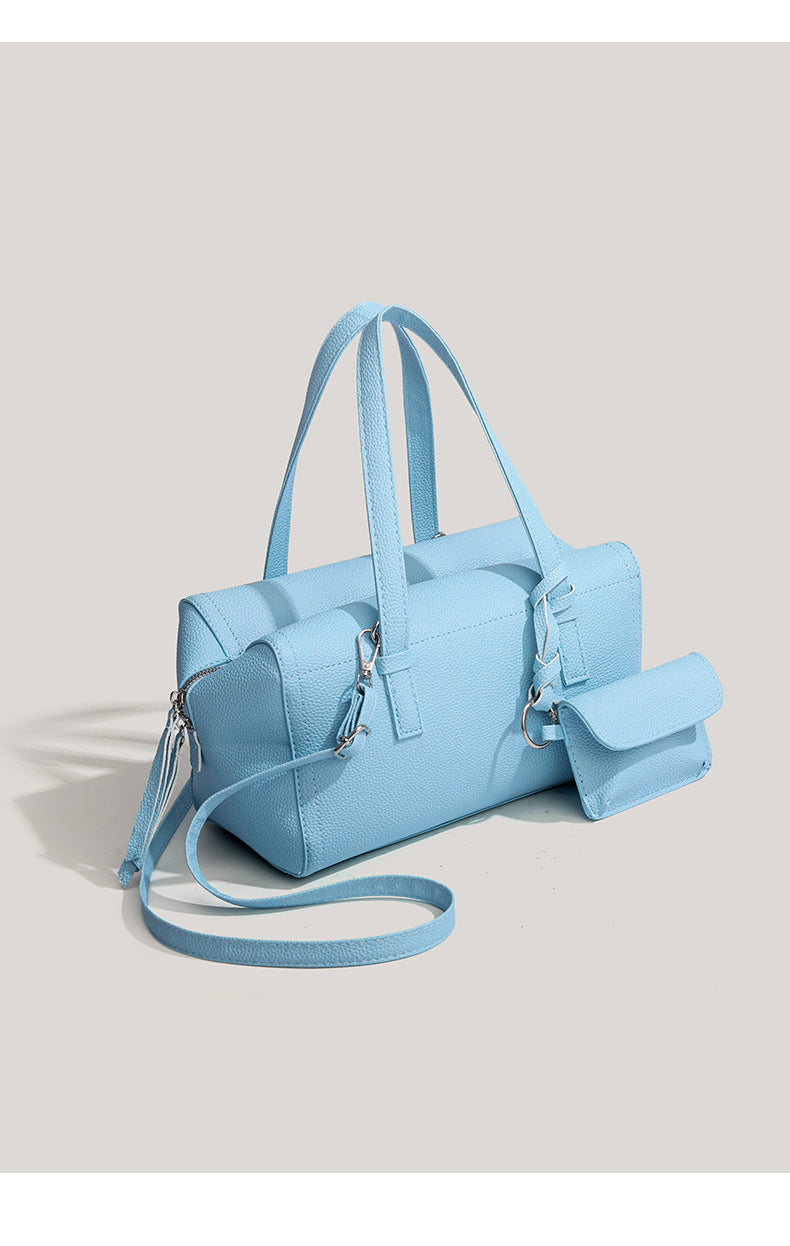 Light blue pebbled matte Boston tote bag with top handles, detachable shoulder strap, metal ring hardware, and matching mini