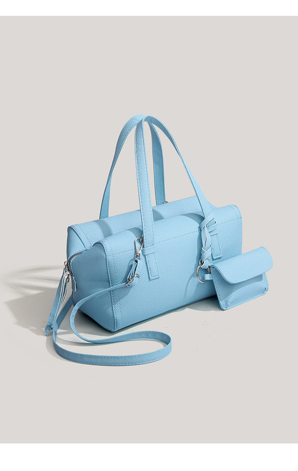 Light blue pebbled matte Boston tote bag with top handles, detachable shoulder strap, metal ring hardware, and matching mini