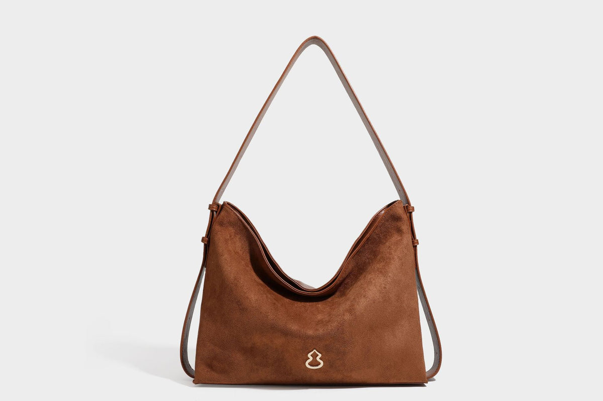 Slouchy suede-finish brown shoulder bag with long single strap and small gold-tone logo emblem on front, detail view 41