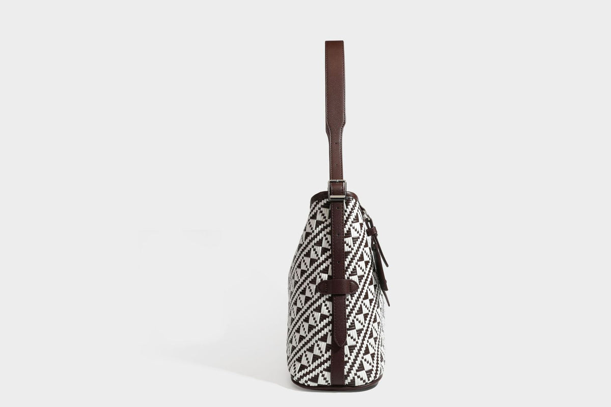 Woven geometric bucket shoulder bag in white and dark brown two-tone pattern with leather-look trim and drawstring top