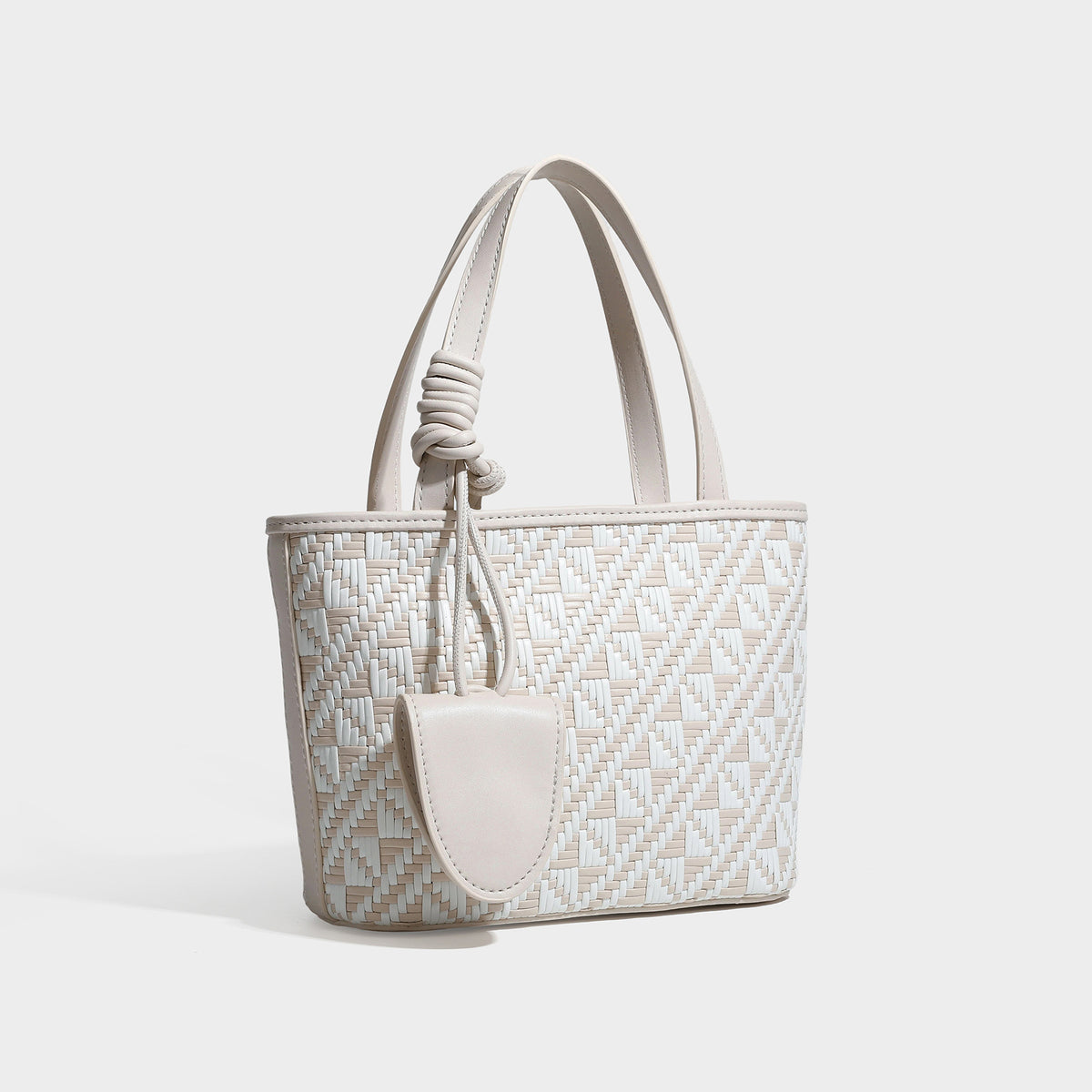 Kleiner, strukturierter Shopper mit gewebtem geometrischem Muster, glatten Besätzen in Lederoptik, geknoteten Henkeln, Reißverschluss und herabhängendem Frontdetail