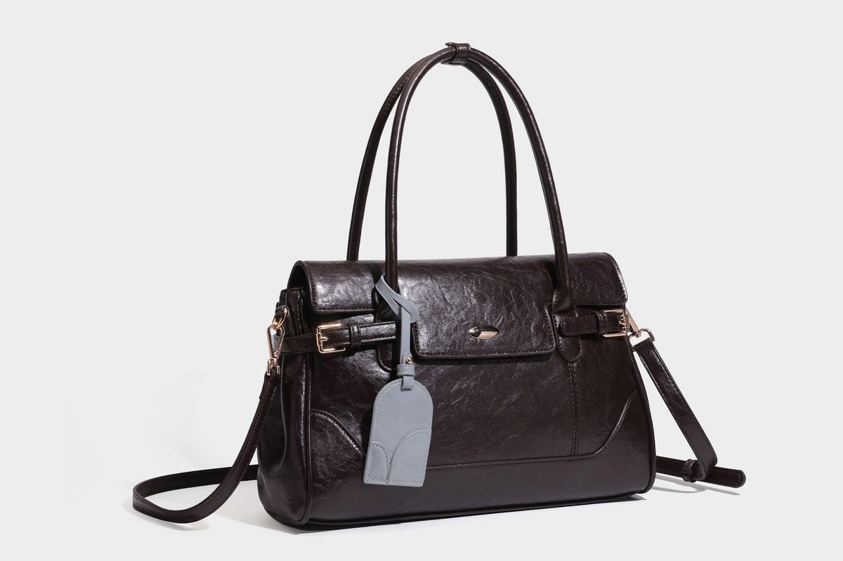 Structured glossy leather-look satchel bag with flap closure, gold-tone buckle accents, double top handles, detachable