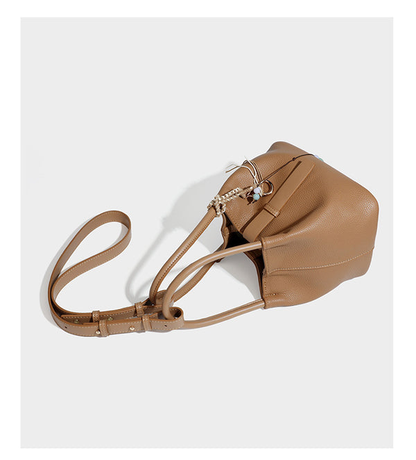 Pebbled leather-look bucket tote bag with rolled double handles, drawstring closure, braided cord charm, and detachable