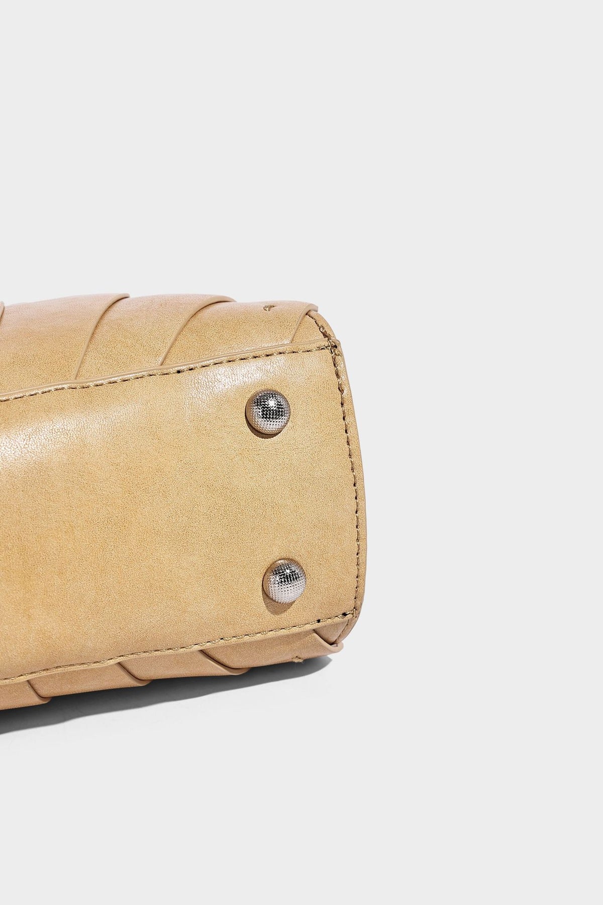Structured dome satchel with fan-pleated leather-look exterior, dual top handles, and detachable shoulder strap, detail view