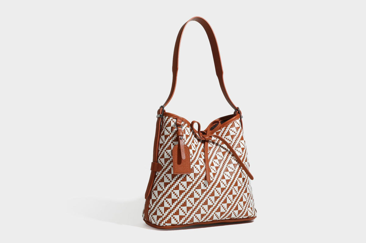 Woven geometric bucket shoulder bag in white and dark brown two-tone pattern with leather-look trim and drawstring top