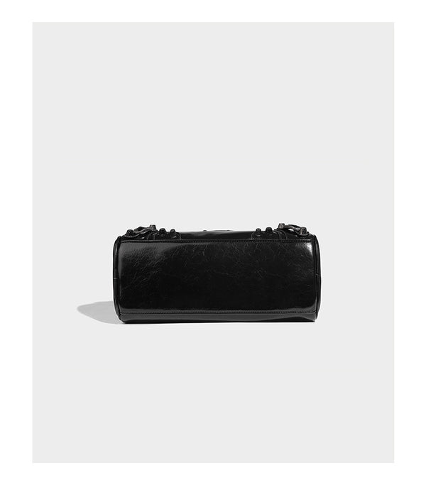 Glossy studded mini satchel bag with braided top handles, front zip pocket, heart charm, and detachable crossbody strap
