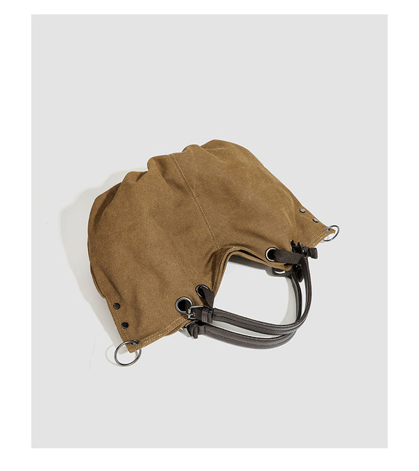 Slouchy matte canvas tote bag with dark dual top handles, metal grommet hardware, and detachable long shoulder strap, detail