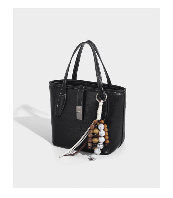 Compact structured bucket tote bag with pebbled textured finish, dual top handles, silver-tone lock hardware, and detachable