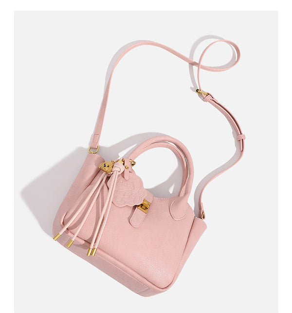 Small structured pebbled leather-look mini tote bag with gold-tone hardware, front toggle closure, knotted bear tassel charm