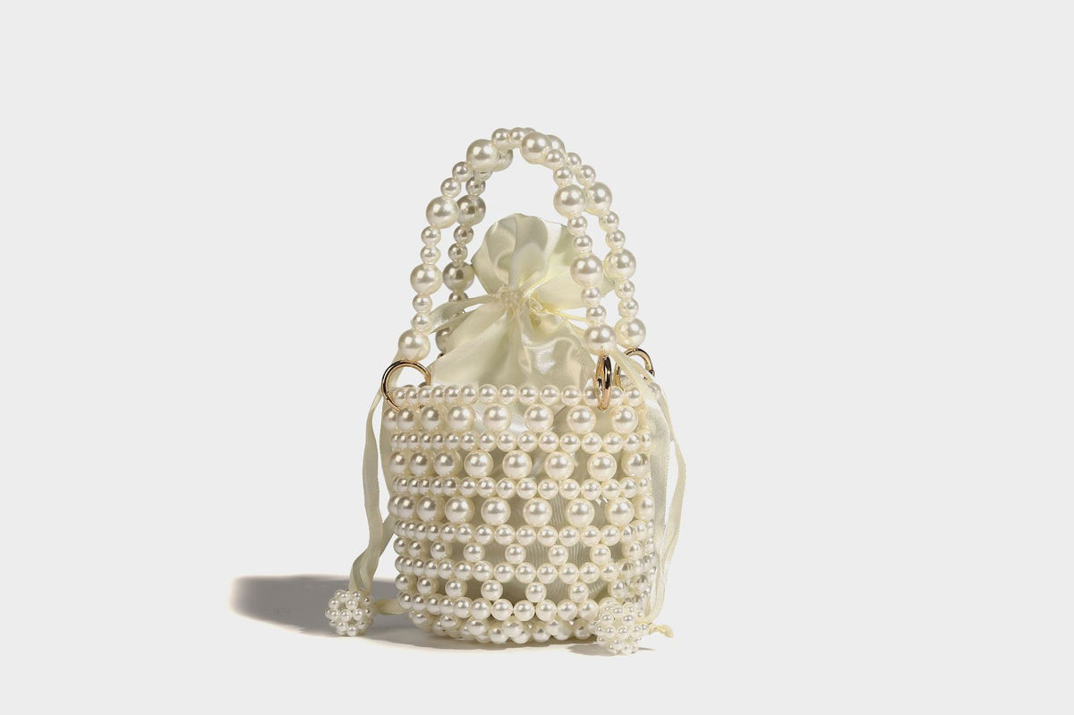Elfenbeinfarbene Mini-Bucket-Bag aus Kunstperlen mit Satin-Innenbereich und Zugband, goldfarbenen Ringbeschlägen und gewölbtem Perlenhenkel an der Oberseite