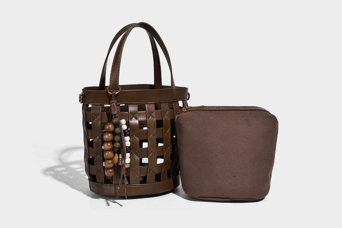 Small woven lattice bucket bag in brown leather-look finish with beaded tassel charm, dual top handles, and detachable