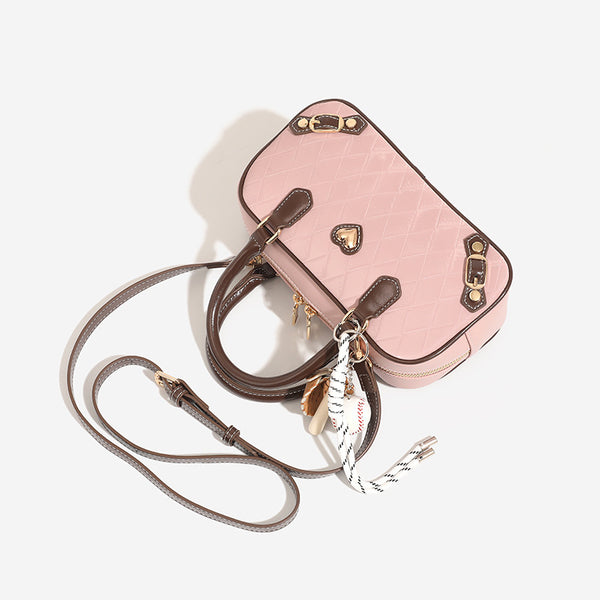 Blush pink quilted bowling barrel bag with dark brown leather-look trim and handles, baseball bat and ball charm, gold-tone