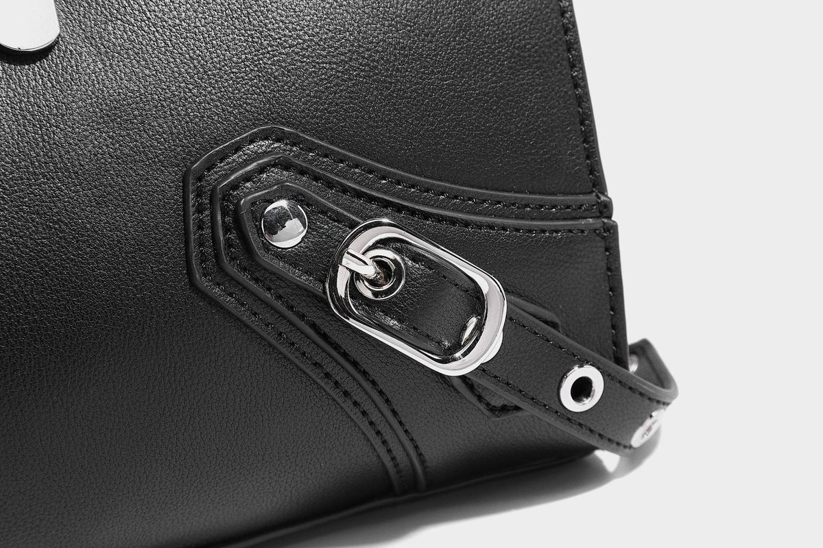 Black structured rectangular satchel bag with silver-tone rivets, large front buckle strap, zip pockets, dual top handles