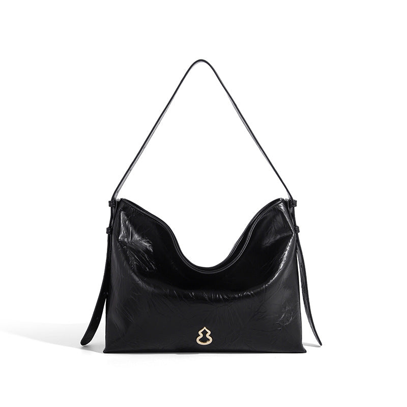 Large slouchy hobo shoulder bag in glossy crinkle leather-look finish with gold-tone emblem hardware and adjustable strap