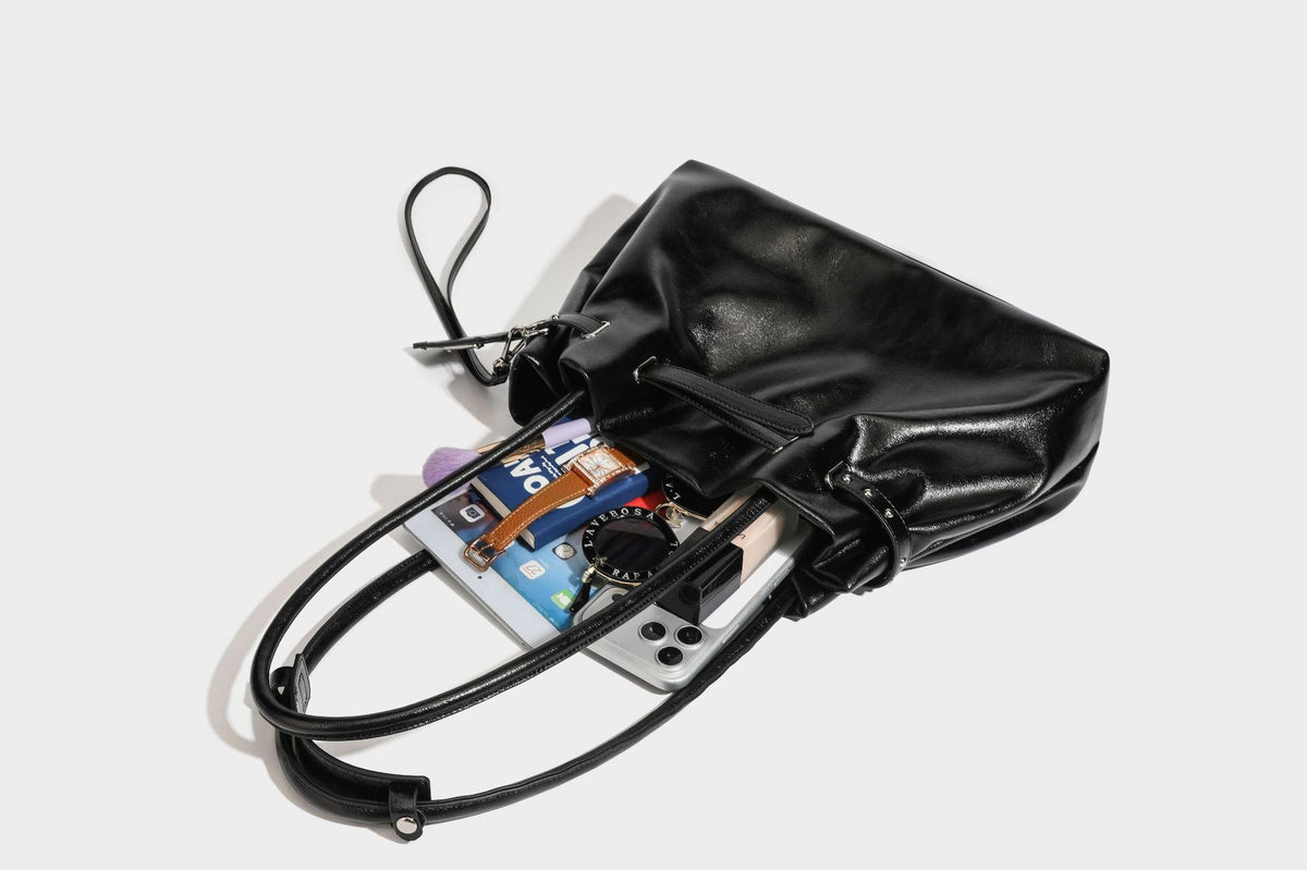 Glänzende schwarze, weich fallende Schultertasche mit gerafftem Abschluss, zwei langen Trageriemen, silberfarbenen Beschlägen und abnehmbarem Umhängeriemen