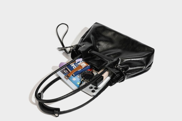 Glänzende schwarze, weich fallende Schultertasche mit gerafftem Abschluss, zwei langen Trageriemen, silberfarbenen Beschlägen und abnehmbarem Umhängeriemen