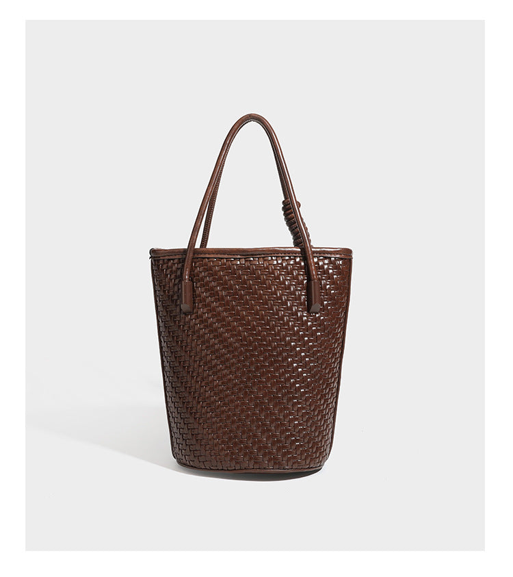 Structured woven-texture leather-look bucket bag in brown with knotted top handles, small front flap pouch, and adjustable