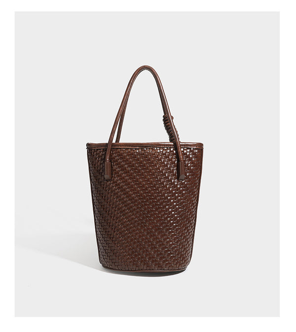 Structured woven-texture leather-look bucket bag in brown with knotted top handles, small front flap pouch, and adjustable