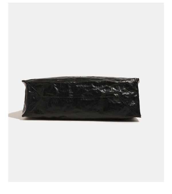 Large glossy crinkled rectangular tote bag with long double handles and hanging envelope snap tag, detail view 9