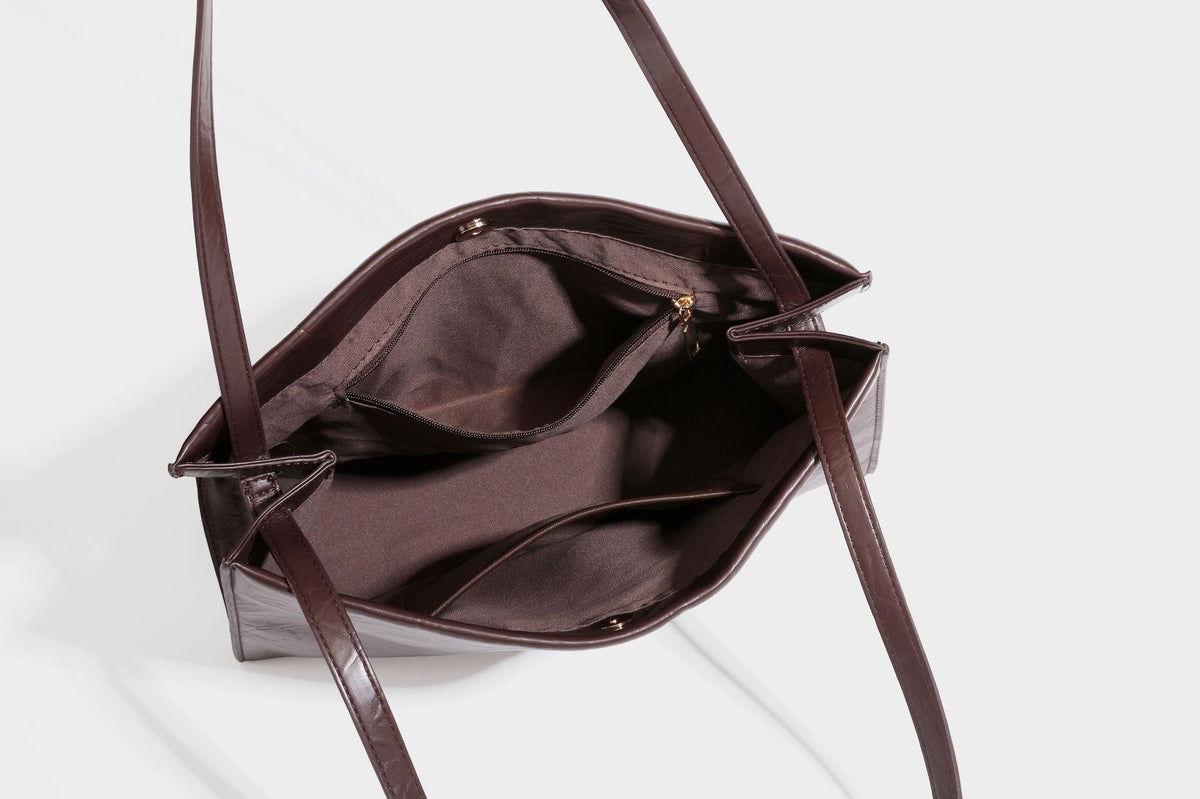 Strukturierte rechteckige Tote-Schultertasche aus glänzender, geknitterter Lederoptik mit langen Doppelträgern und Emblem in Goldoptik