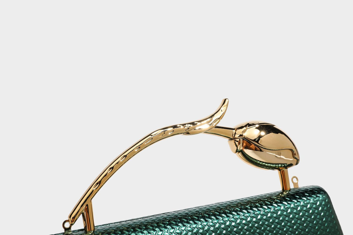 Structured rectangular metallic woven clutch bag with sculptural gold-tone leaf top handle and detachable chain strap, detail
