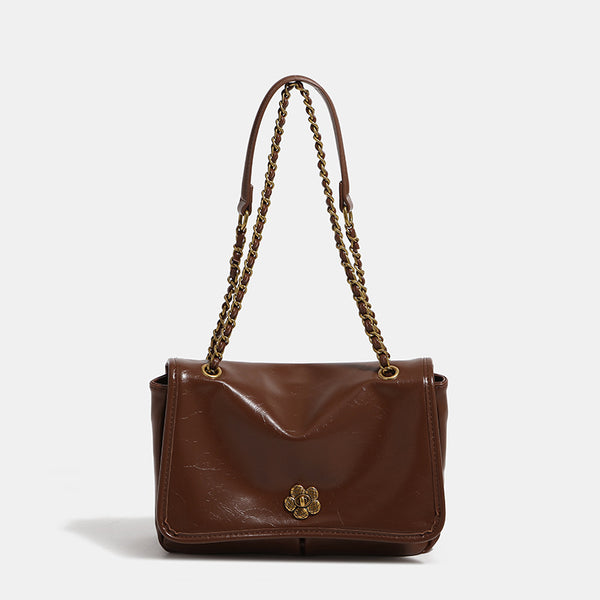 Structured flap shoulder bag with antique gold-tone chain strap and flower turn-lock clasp in crinkled leather-look finish