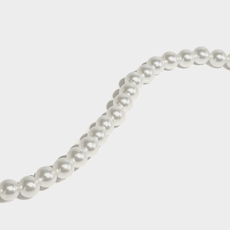 Small boxy pearl-bead mini top-handle bag with silver metallic bead accents, satin floral detail, and long beaded shoulder