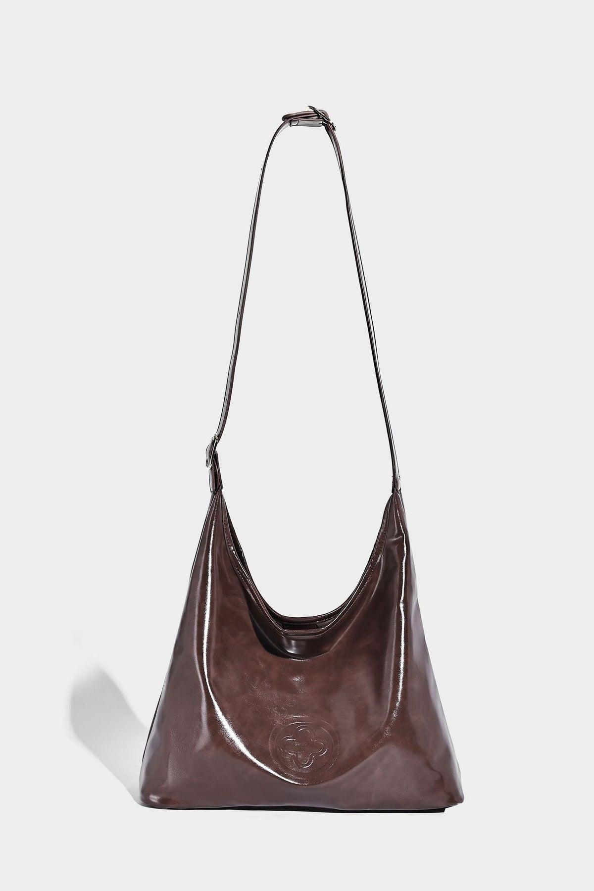 Glossy slouchy hobo shoulder bag with adjustable strap and embossed floral emblem, detail view 25