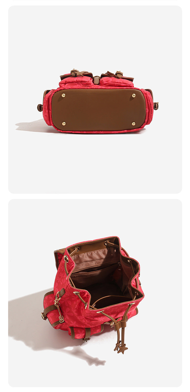 Red floral-print backpack handbag with brown leather-look trim, dual front buckle pockets, star charms, and gold-tone, detail