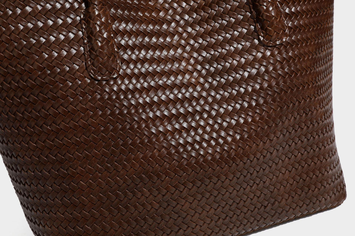 Large open-top woven leather-look tote bag in dark brown with scalloped edge, braided double shoulder straps, and decorative