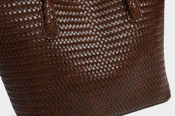 Large open-top woven leather-look tote bag in dark brown with scalloped edge, braided double shoulder straps, and decorative