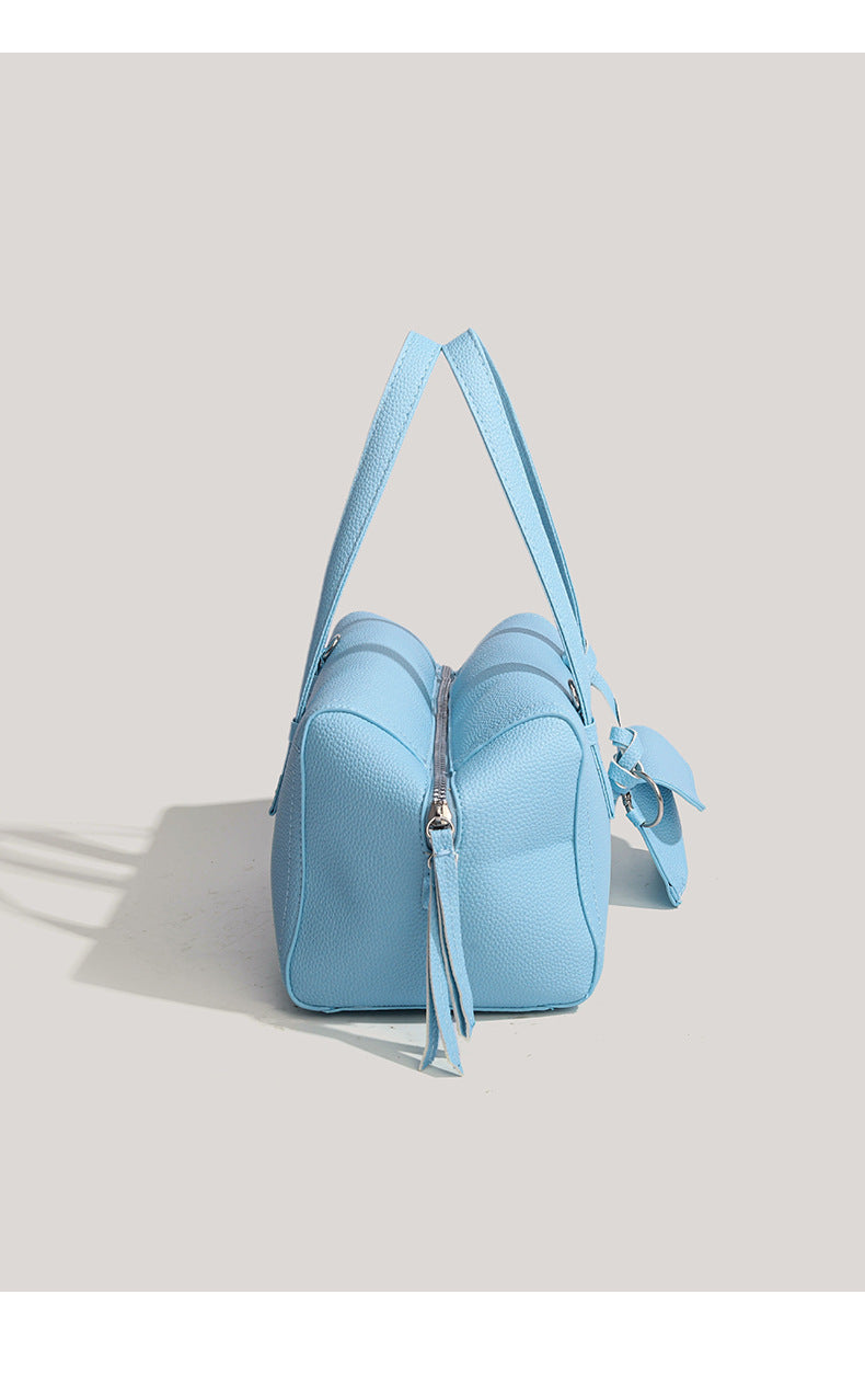 Light blue pebbled matte Boston tote bag with top handles, detachable shoulder strap, metal ring hardware, and matching mini
