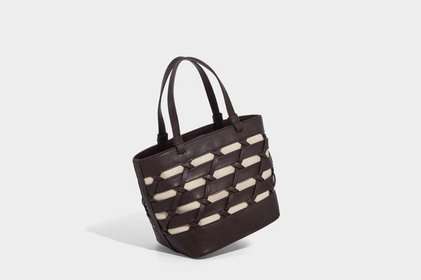 Structured woven lattice tote bag with cream lining, dual top handles, detachable crossbody strap, and silver-tone hardware