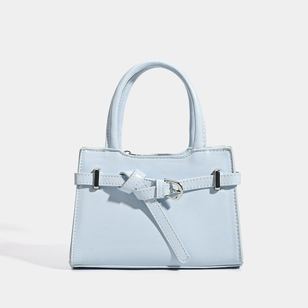 Small structured trapezoid mini top-handle bag with front belt-knot buckle detail and glossy leather-look finish, front view