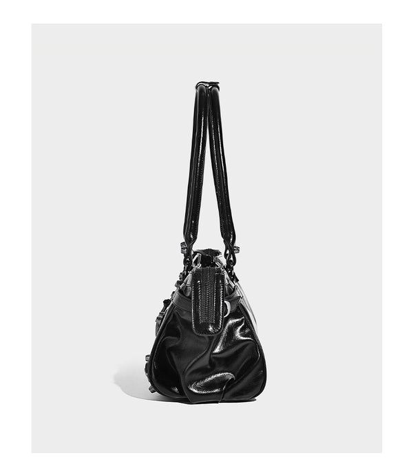 Längliche Barrel-Schultertasche mit glänzender Oberfläche in Lederoptik, silberfarbenen Nieten, seitlichen Quasten und mehreren äußeren Reißverschlüssen