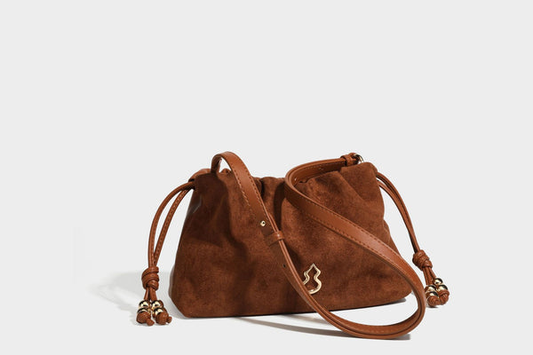 Suede-look drawstring shoulder bag in brown with smooth trim, knotted bead drawstring closure, slim adjustable strap, and