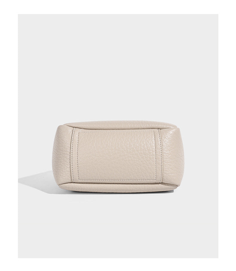 Small structured pebbled bucket tote with double top handles, silver turn-lock hardware, and detachable shoulder strap